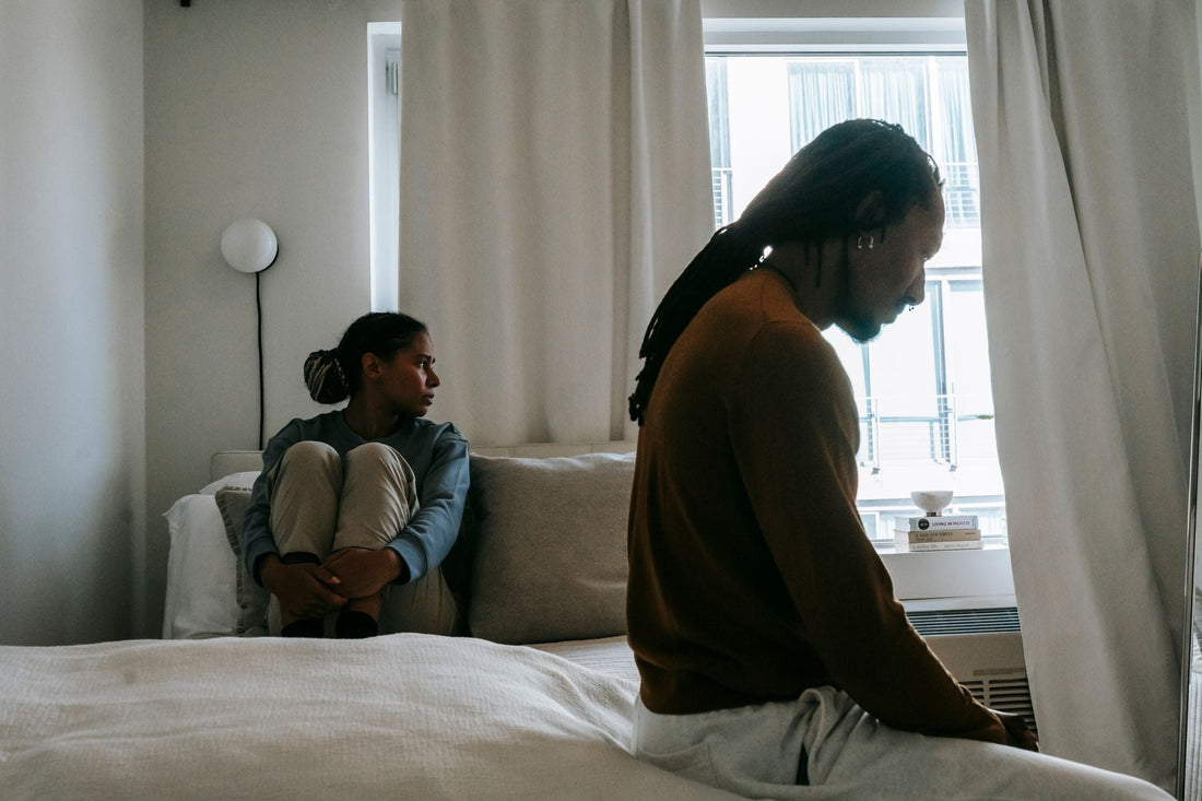 Un couple distant assis dans une chambre, illustrant les difficultés de communication et le sentiment d'isolement lors d'une baisse de désir ou de libido dans le couple.
